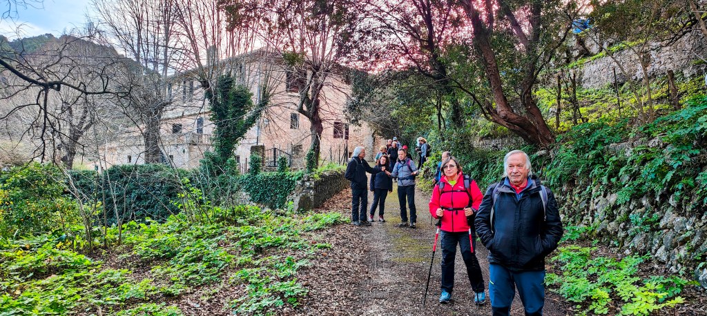 Grupo de senderistas en un camino rodeado de naturaleza, con Son Brondo al fondo .