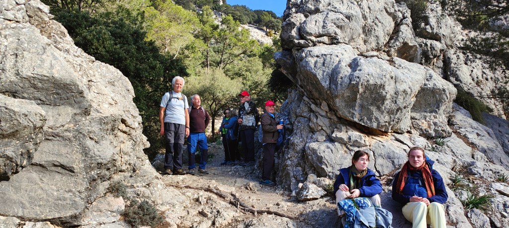 Grupo de personas en un sendero de montaña rodeado de rocas y vegetación.