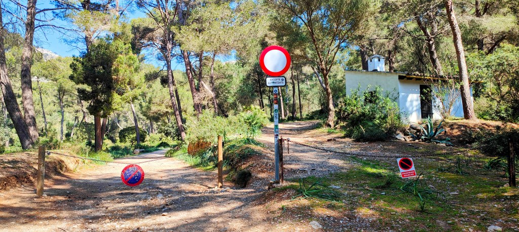 Camino con barrera y señales de prohibición en un entorno forestal.